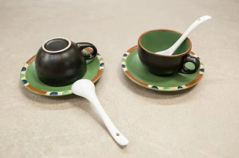 Two black ceramic cups for coffee on green saucers with spoons Stock Photos