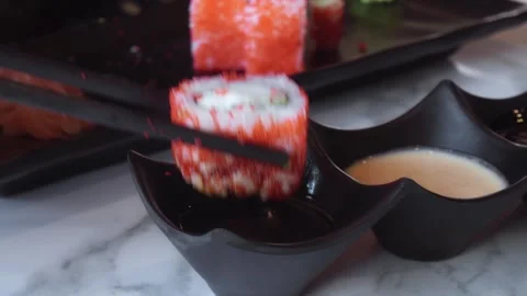 Two black ceramic dipping bowls filled with soy sauce and sesame dressing sit on Stock Footage 312741680