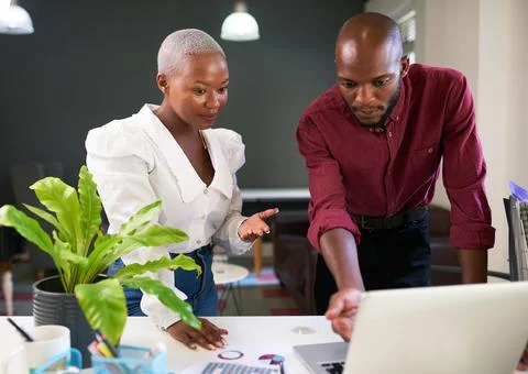 Two Black colleagues discuss work presentation on laptop Stock Photos