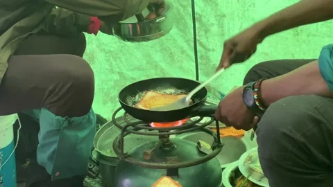Two black cooks prepare hot sandwiches in a pan on a gas bottle in a tent Vídeo Stock 168732817