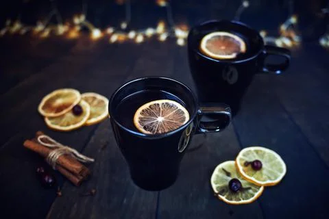 Two black cups of tea with lemon on a dark background. lemon slices, cinnamon Stock Photos