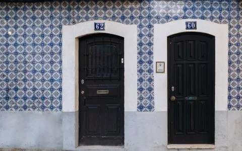 Two black doors in front of rustic old house with blue azulejo tiles walls. T Stock Photos