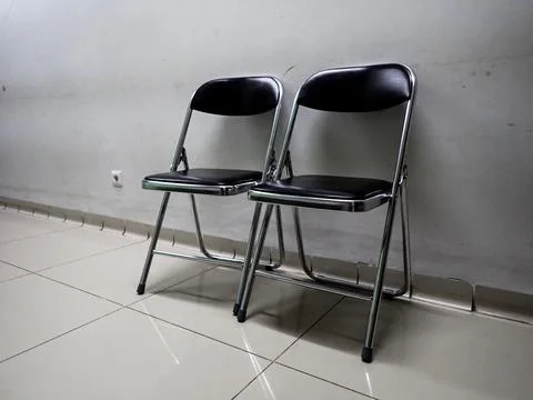 Two black folding chairs in front of the wall Fotos de archivo