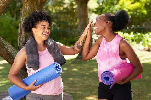 Two Black friends high five in the park after doing yoga, with mats and towels Stock Photos