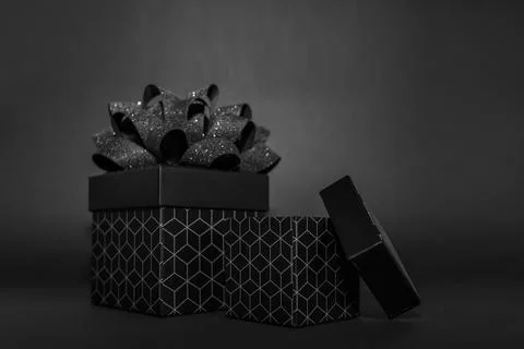 Two black gift box with a geometric pattern and a black bow on a black back.. Stock Photos