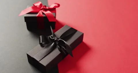 Two black gift boxes with red and black ribbons on black and red background with Stock Footage 336304810