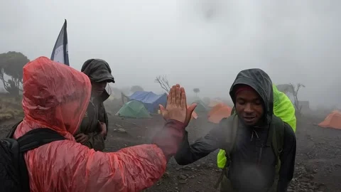 Two black guides congratulate their friends on their arrival at Shira Cave Camp Video stock 169337850