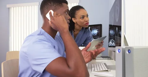 Two Black medical specialists using computer to review information together Video stock 42669997