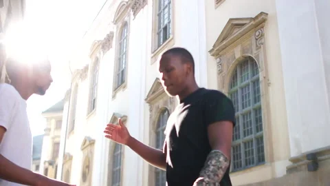 Two black men met in the middle of the street. They shake hands and hug. Sun Stock Footage 133722617