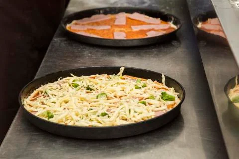 Two black metal baking sheets with raw pizza. Stock Photos