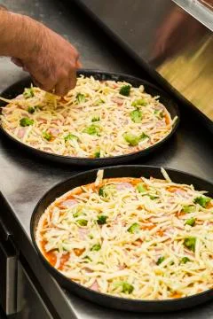 Two black metal baking sheets with raw pizza. Stock Photos