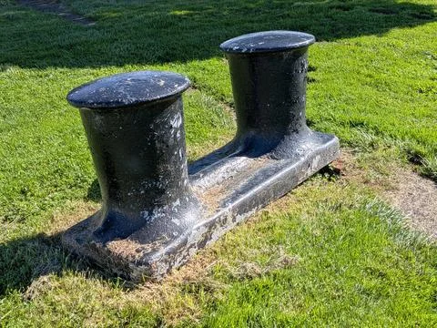 Two black metal cylinders displayed outdoors near a coastal park Photos