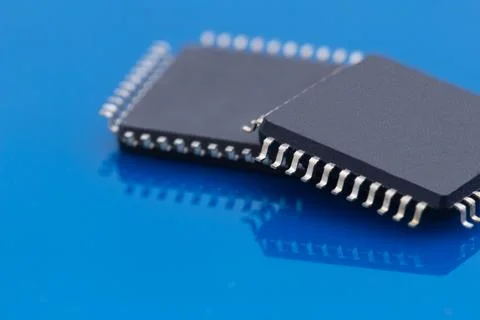 Two black microchips rest on a smooth blue surface Stock Photos