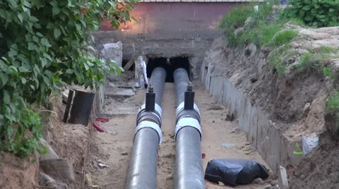 Two black new water heating pipes in ditch going into house Stock Footage 55868819