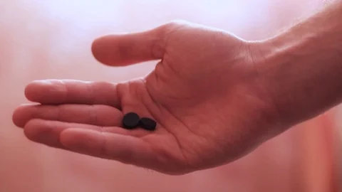 Two black pills on the palm Stock Footage 98176149