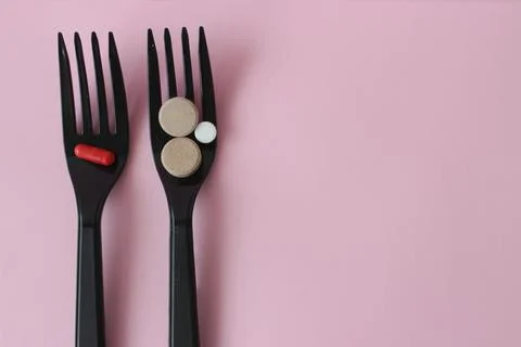 Two black plastic forks with colored tablets on a color background. Stock Photos