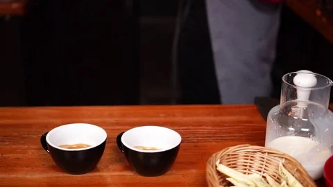 Two black small minimalistic cappuccino cups on wooden bar counter at cozy cafe Stock Footage 105453601