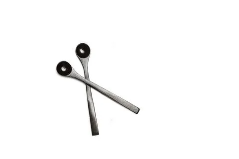 Two black spoons on a white background with copy space Stock Photos