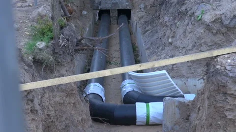 Two black water heating pipes in a ditch going into the house Video stock 55864345