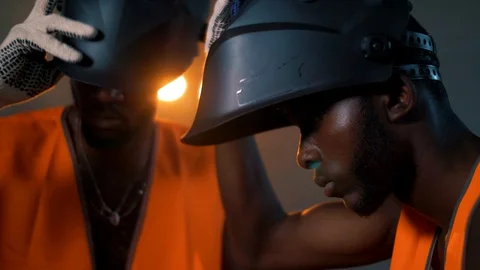 Two black welders put on their welding masks synchronously before starting work Video stock 128748215