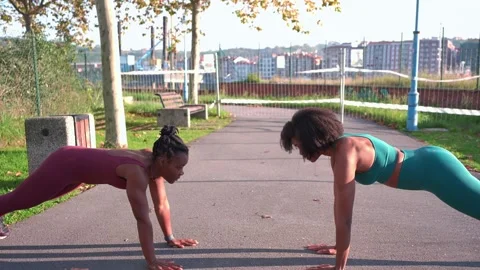 Two black women doing push ups and giving high five in a park Stock Footage 316687698