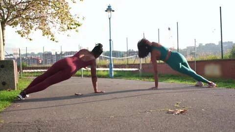 Two black women doing side plank exercise outdoors Stock Footage 316688248