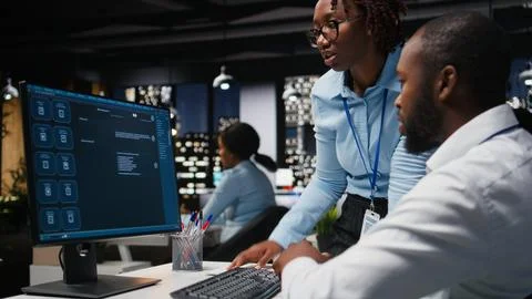 Two black workers interacting with a virtual assistant on computer at desk Stock Photos