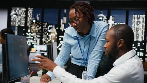 Two black workers interacting with a virtual assistant on computer at desk Stock Photos