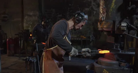 Two blacksmiths forge parts in a forge Видео 144518619