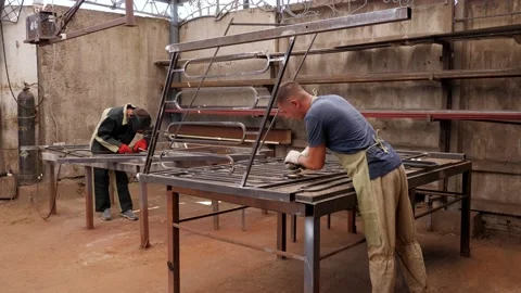 Two blacksmiths in working uniforms make a metal fence in the forge. Stock Footage 218446086