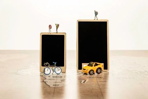 Two blank black boards with tiny human model with car and bicycle on world map Stock Photos