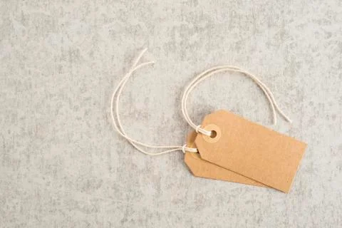 Two blank paper tags with string on stone table Stock Photos