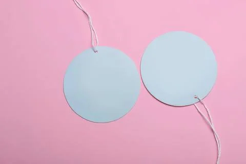 Two blank round tags hanging on pink background Stock Photos