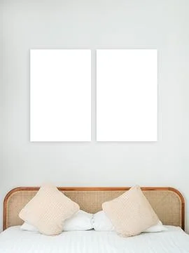 Two blank vertical white frames on soft gray wall above bed with pillows an.. Foto stock