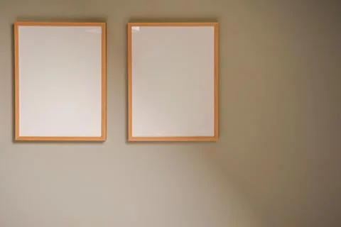 Two blank white frames on a beige wall, ready for content, creating an empt.. Stock Photos