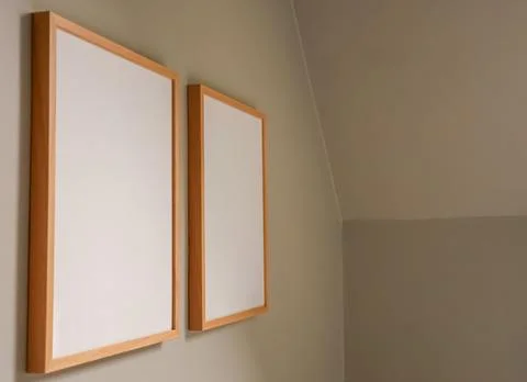Two blank wooden frames hanging on a beige wall providing copy space for yo.. Stock Photos