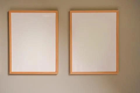 Two blank wooden frames hanging on a neutral wall, providing a clear mockup.. Stock Photos