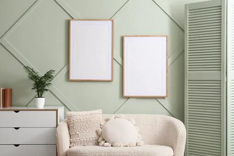 Two blank wooden frames on a sage green wall with decorative molding, modern  Stock Photos