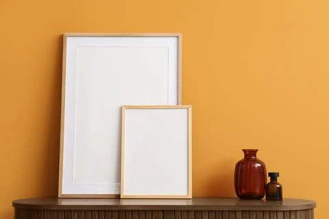 Two blank wooden picture frames and decorative vases on a dark wooden cabinet Stock Photos