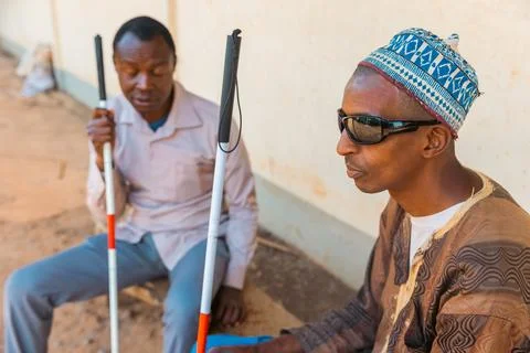 Two blind men sitting on a bench chatting, disabled people together Stock Photos