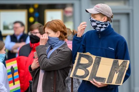 Two BLM protesters adjust their protective face coverings while holding a hom Stock Photos