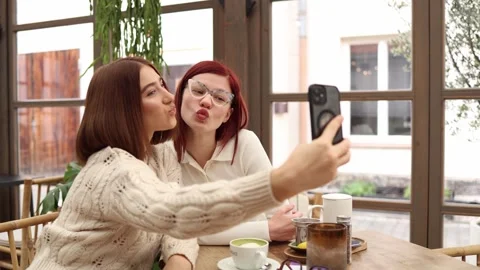 Two bloggers sit together making a duck face selfie  Stock Footage 320827275