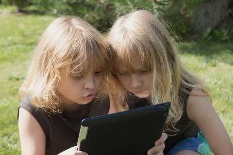 Two blond boys are playing with the tablet outdoors Stock Photos