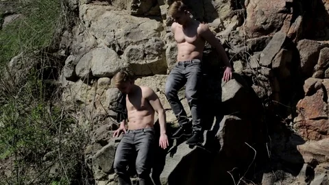 Two blond men on the rocks with a naked | Stock Video | Pond5