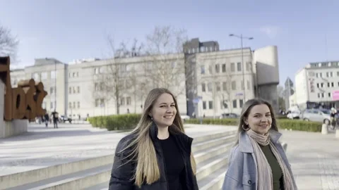 Two blonde girls are walking and chatting in the city Stock Footage 305392353