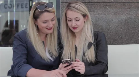 Two blondes are sitting in a café and discuss photos in the smartphone Vídeo Stock 64221172