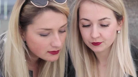 Two blondes are sitting in a café and discuss photos in the smartphone Stock Footage 64230893