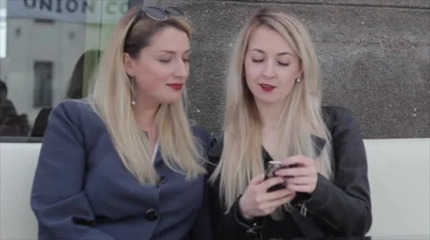 Two blondes are sitting in a café and discuss photos in the smartphone 库存影片 64231837
