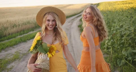Two blondes are walking in the field with a bouquet of flowers Stock Footage 204145224