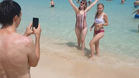 Two blondes in a bikini on the shore of the clear blue sea are photographed. 動画素材 124080083